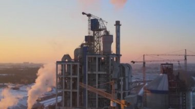 Yüksek beton fabrikası ve endüstriyel üretim alanında kule vinçleri olan çimento fabrikasının havadan görüntüsü. Sera gazı atmosferi kirletiyor. Üretim ve küresel sanayi kavramı.