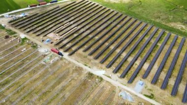 Elektrik santralinin inşaat halindeki hava görüntüsü. Kamyon, elektrik enerjisi üretmek için metal çerçevedeki güneş panelleri için montaj parçaları dağıtıyor. Yenilenebilir elektriğin geliştirilmesi