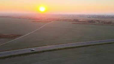 Gün batımında hızlı giden arabalarla şehirlerarası yol manzarası. Akşamları otoban trafiğinin insansız hava aracı görüntüsü