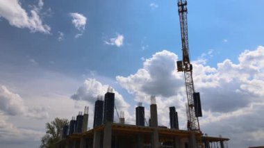 İnşaat halindeki yüksek beton binadaki vinç ve işçiler. Gayrimenkul geliştirme kavramı