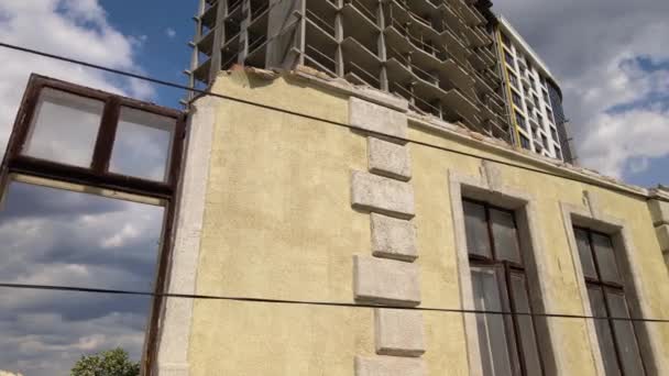 Architectonische detail van hoge frame van monolithische betonnen gebouw in aanbouw en oude gesloopt huis in de voorkant. Ontwikkeling van onroerend goed — Stockvideo