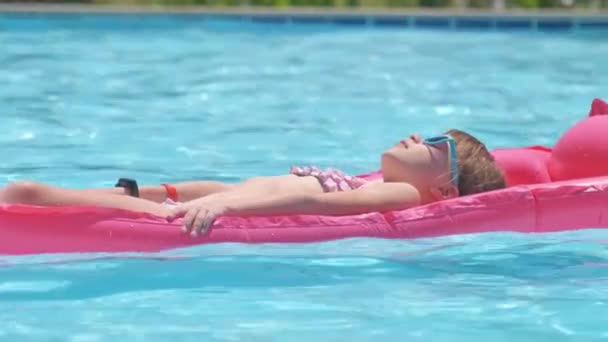 Young child girl relaxing on summer sun swimming on inflatable air mattress in swimming pool during tropical vacations. Summertime activities concept — Stock Video