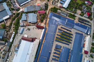 Sanayi binasının çatısına yeşil ekolojik elektrik üretmek için monte edilen mavi fotovoltaik güneş panellerinin hava görüntüsü. Sürdürülebilir enerji konsepti üretimi