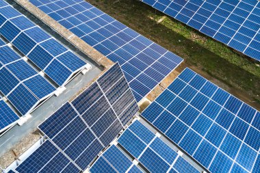 Sanayi binasının çatısına yeşil ekolojik elektrik üretmek için monte edilmiş mavi fotovoltaik panelli güneş enerjisi santralinin hava görüntüsü. Sürdürülebilir enerji konsepti üretimi