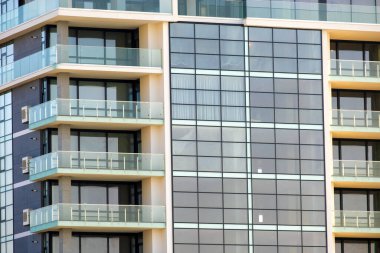 Birçok pencere ve balkonu olan modern yüksek apartman cephesinin mimari ayrıntıları