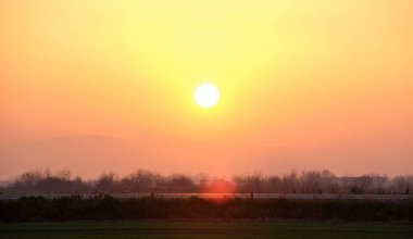 Güzel bir akşam panoramik manzarası. Gün batımında güneş batarken uzak dağ tepeleri ve asfalt yolda batıyor.