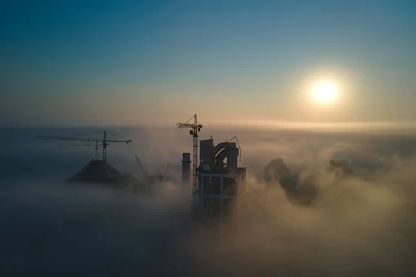 Luchtfoto van cementfabriek met hoge betonnen installatiestructuur en torenkraan op industriële productielocatie op mistige ochtend. Fabricage en mondiaal industrieconcept — Stockfoto