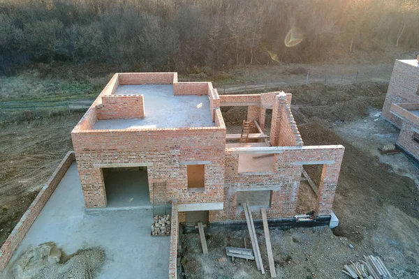 Kenar mahallelerde inşaat halindeki tuğla iskelet duvarları olan yeni evlerin havadan görünüşü. Modern şehir banliyölerinde gayrimenkul geliştirme