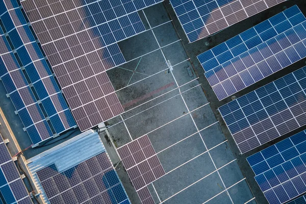 Vista aérea de usina de energia solar com painéis fotovoltaicos azuis montados no telhado de construção industrial para a produção de eletricidade ecológica verde. Produção de conceito de energia sustentável — Fotografia de Stock