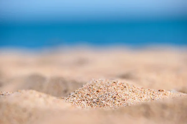 Detailní záběr na čistý žlutý povrch písku pokrývající přímořskou pláž s modrou mořskou vodou na pozadí. Koncept cestování a dovolené — Stock fotografie