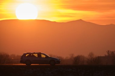 Gün batımında şehir içi yolda hızlı giden bir araba. Akşamları otoyol trafiği