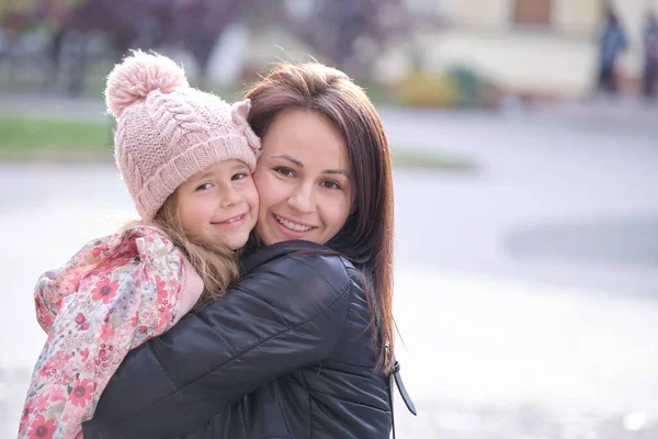 Ung vacker kvinna kramar kärleksfullt sin dotter. Lycka i familjeförhållanden koncept — Stockfoto