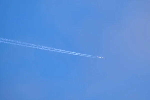 遠くの旅客機は、澄んだ青い空に高い高度を飛んで、白い煙の跡を後ろに残しています。航空交通の概念 — ストック写真