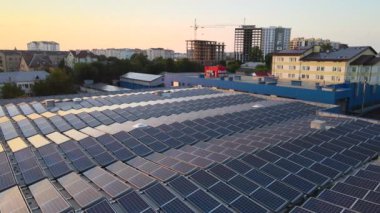 Sanayi binasının çatısına yeşil ekolojik elektrik üretmek için monte edilmiş mavi fotovoltaik panelli güneş enerjisi santralinin hava görüntüsü. Sürdürülebilir enerji konsepti üretimi