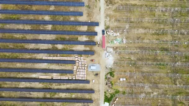 電気エネルギーを生産するための金属フレーム上の太陽電池パネルの組立部品を提供トラックと建設中の電気発電所の空中ビュー。再生可能エネルギーの開発 — ストック動画