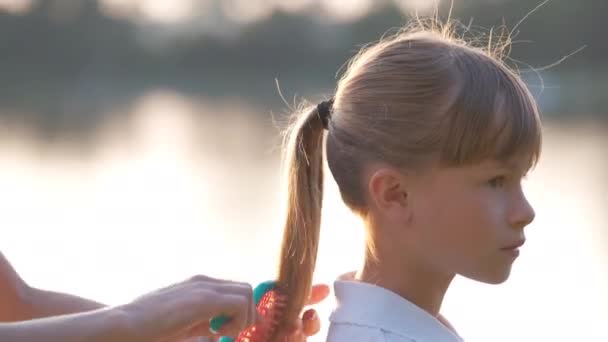 Mutter kämmt Haare ihrer Tochter im Sommerpark mit Bürste — Stockvideo
