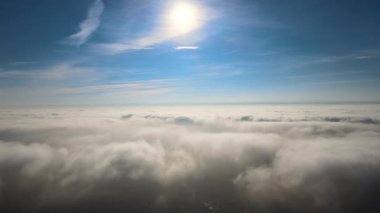Güneşli bir günde, yeryüzünün yüksek irtifasından beyaz kabarık kümülüs bulutlarıyla kaplı hava manzarası.