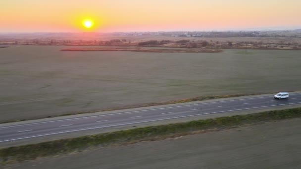 Luchtfoto van het personenbusje dat bij zonsondergang snel over de intercity road rijdt. Snelwegverkeer in de avond — Stockvideo