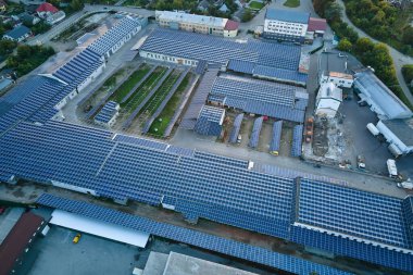 Sanayi binasının çatısına yeşil ekolojik elektrik üretmek için monte edilmiş mavi fotovoltaik panelli güneş enerjisi santralinin hava görüntüsü. Sürdürülebilir enerji konsepti üretimi