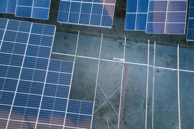 Sanayi binasının çatısına yeşil ekolojik elektrik üretmek için monte edilmiş mavi fotovoltaik panelli güneş enerjisi santralinin hava görüntüsü. Sürdürülebilir enerji konsepti üretimi