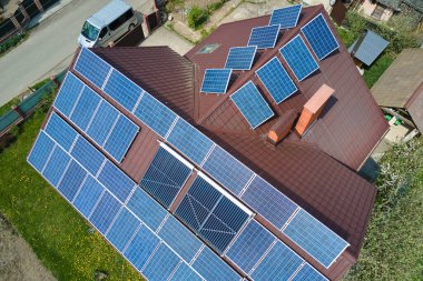 Banliyö bölgesinde temiz ekolojik elektrik enerjisi üretmek için güneş fotovoltaik panellerle kaplı çatısı olan bir ev. Özerk konut kavramı