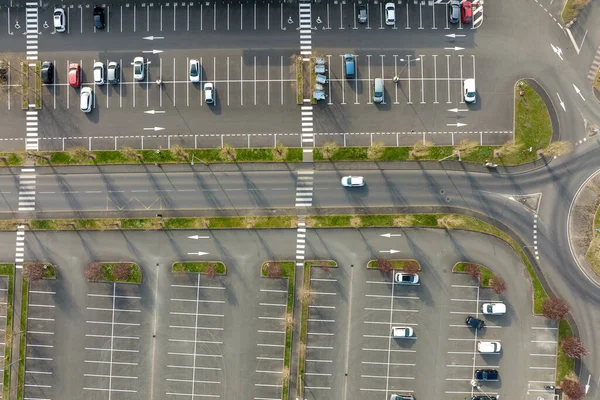 Вид с воздуха на много красочных автомобилей, припаркованных на стоянке с линиями и разметками для парковки и направления — стоковое фото