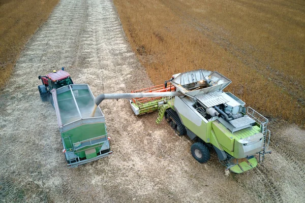大規模な熟した小麦畑で収穫シーズン中に働く貨物トレーラーに収穫機の荷役穀物を組み合わせるの空中ビュー。農産物のコンセプトの農業と輸送 — ストック写真