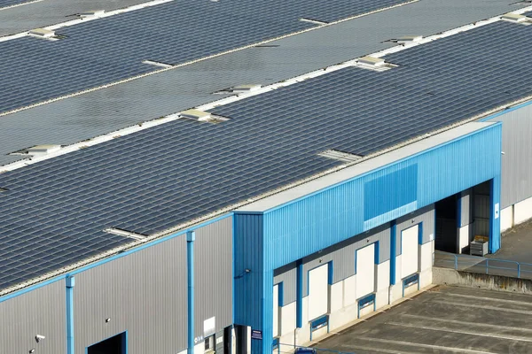 Vista aérea de paneles solares fotovoltaicos azules montados en el techo de un edificio industrial para producir electricidad ecológica verde. Producción del concepto de energía sostenible —  Fotos de Stock