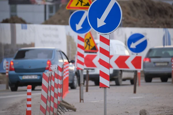 Дорожні роботи попереджають про дорожні знаки будівельних робіт на міській вулиці і повільно переміщують автомобілі — стокове фото