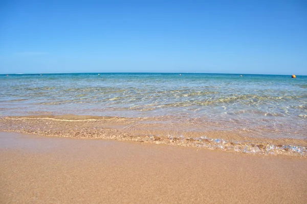 Paesaggio marino con superficie di acqua di mare blu con piccole onde ondulate che si infrangono sulla spiaggia di sabbia gialla. Concetto di viaggio e vacanze — Foto Stock