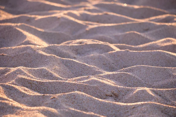 Primer plano de la superficie de arena amarilla limpia que cubre la playa junto al mar iluminada con luz nocturna. Concepto de viajes y vacaciones —  Fotos de Stock