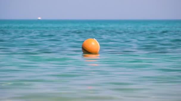 Narancssárga bója lebeg a tenger felszínén. Az emberi életbiztonság fogalma — Stock videók