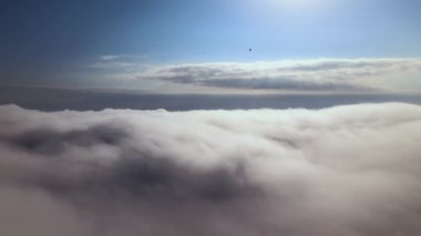 Dünya 'nın yüksek irtifasındaki uçak penceresinden hava manzarası beyaz kabarık kümülüs bulutlarıyla kaplı.