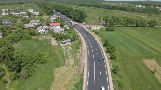 Luftaufnahme der Überlandstraße zwischen grünen landwirtschaftlichen Feldern mit schnell fahrenden Autos. Draufsicht von der Drohne auf den Autobahnverkehr — Stockvideo