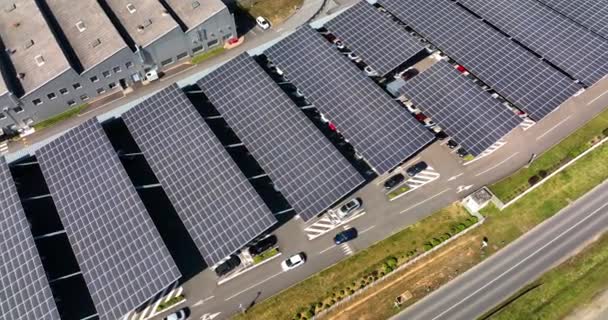 Luftaufnahme von Sonnenkollektoren, die als Schattendach über einem Parkplatz mit geparkten Autos zur effektiven Erzeugung sauberen Stroms installiert sind. Photovoltaik-Technologie in städtische Infrastruktur integriert — Stockvideo