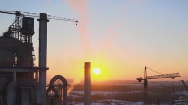 Gün batımında endüstriyel üretim alanında yüksek beton yapılı çimento fabrikası kulesinin havadan görüntüsü. Üretim ve küresel sanayi kavramı