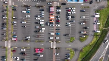 Otoparkta park yerleri ve yönler için çizgiler ve işaretlerle park edilmiş birçok renkli arabanın hava manzarası.
