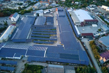 Sanayi binasının çatısına yeşil ekolojik elektrik üretmek için monte edilen mavi fotovoltaik güneş panellerinin hava görüntüsü. Sürdürülebilir enerji konsepti üretimi