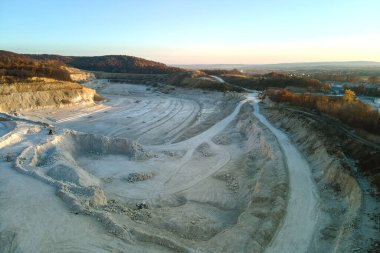 Kazı araçları ve çöp kamyonlarıyla inşaat endüstrisi için kireçtaşı malzemelerinin açık maden sahasının hava görüntüsü