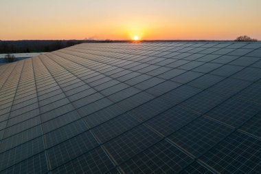 Mavi fotovoltaik güneş panelleri gün batımında temiz ekolojik elektrik üretmek için çatıya monte edildi. Yenilenebilir enerji konsepti üretimi