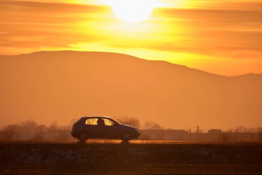 Gün batımında şehir içi yolda hızlı giden bir araba. Akşamları otoyol trafiği