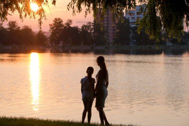 Mutlu anne ve kız el ele tutuşup akşamları yaz parkında eğleniyorlar. Aile sevgisi ve ilişki kavramı
