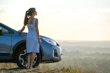 Mavi elbiseli mutlu genç kadın şoför sıcak yaz gününün tadını çıkarıyor. Seyahat ve tatil kavramı