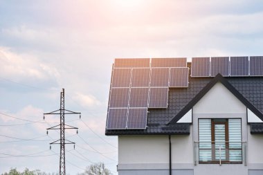 Banliyö bölgesinde temiz ekolojik elektrik enerjisi üretmek için güneş fotovoltaik panellerle kaplı çatısı olan bir ev. Özerk konut kavramı