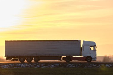 Kargo karavanı olan yarı kamyon akşam vakti otobanda mal taşır. Teslimat ulaşım ve lojistik kavramı