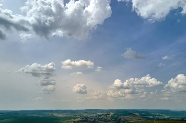 Widok z lotu ptaka na czyste błękitne niebo nad zielonymi uprawnymi polami uprawnymi z uprawami roślin uprawnych i odległym lasem w pogodny letni dzień — Zdjęcie stockowe