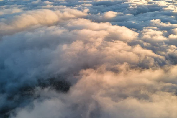 Luftaufnahme von oben in großer Höhe mit dichten, geschwollenen Kumuluswolken, die am Abend fliegen. Erstaunlicher Sonnenuntergang aus Sicht des Flugzeugfensters — Stockfoto