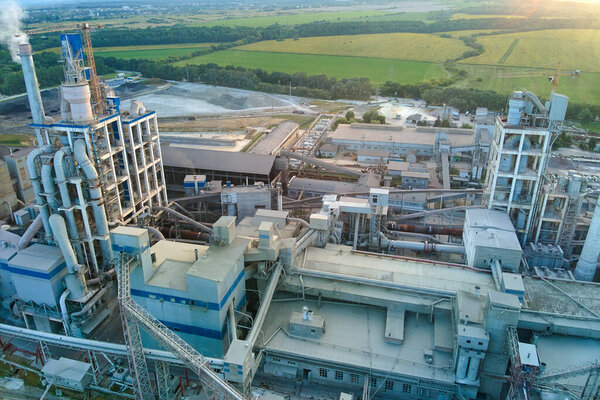 Aerial view of cement factory with high concrete plant structure and tower crane at industrial production site. Manufacture and global industry concept