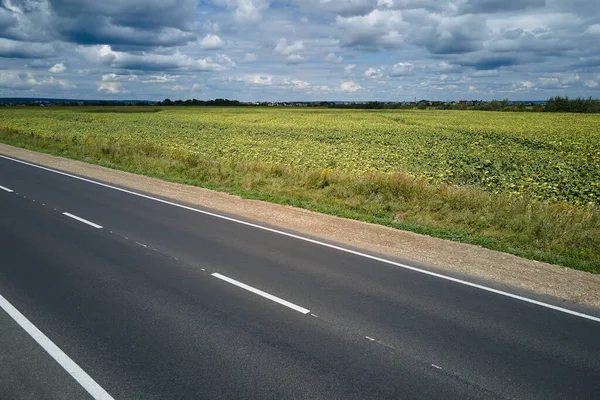 Вид с воздуха на пустую междугороднюю дорогу между зелеными сельскохозяйственными полями. Вид сверху с дрона с шоссе — стоковое фото