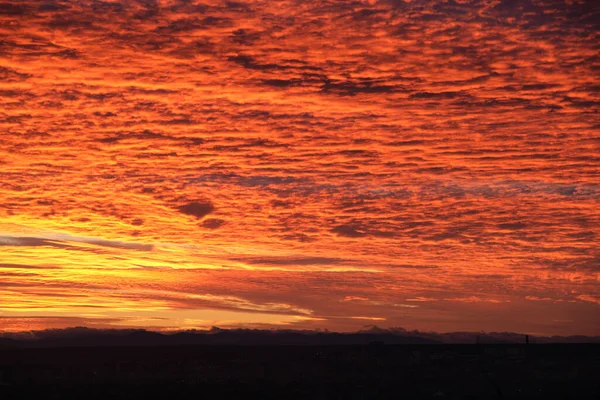 Heldere kleurrijke zonsondergang hemel met levendige gladde wolken verlicht met ondergaande zon licht verspreiden naar de horizon — Stockfoto
